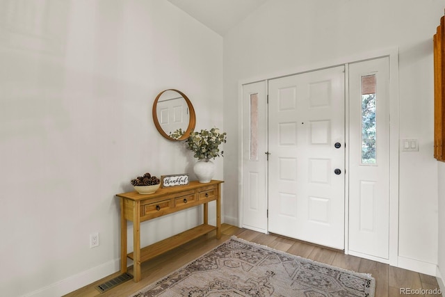 entrance foyer featuring wood-type flooring and lofted ceiling