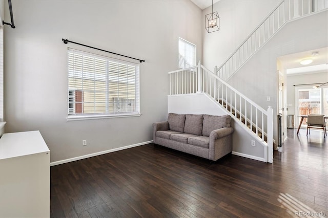 living room with dark hardwood / wood-style flooring, a chandelier, and a high ceiling