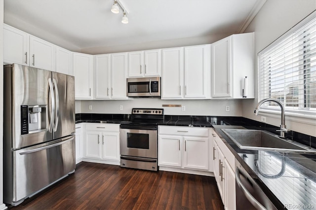 kitchen featuring appliances with stainless steel finishes, white cabinetry, rail lighting, sink, and dark hardwood / wood-style flooring