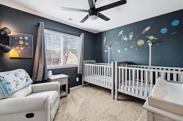 carpeted bedroom featuring ceiling fan and a crib