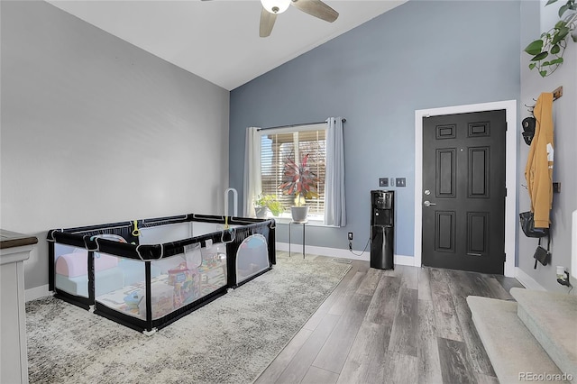 entryway with ceiling fan, high vaulted ceiling, wood finished floors, and baseboards