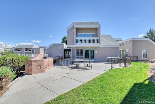 rear view of house featuring a patio area, a yard, and a balcony