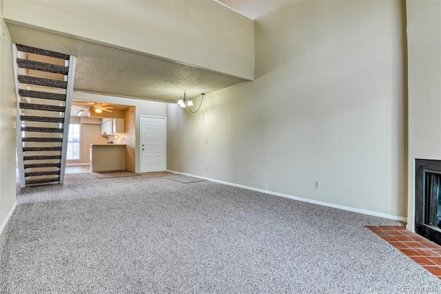 unfurnished living room with carpet floors, a textured ceiling, and an inviting chandelier