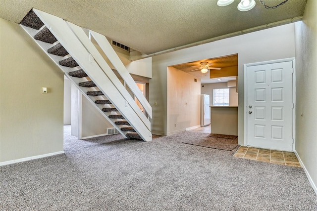 unfurnished living room with carpet, ceiling fan, and a textured ceiling