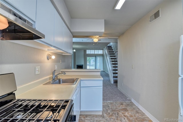 kitchen with kitchen peninsula, ventilation hood, sink, range, and white cabinetry