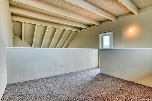 spare room featuring carpet and vaulted ceiling with beams