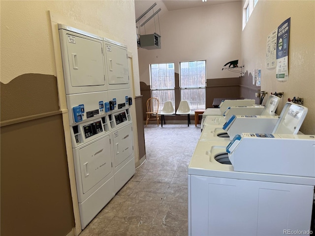 clothes washing area featuring washer and dryer, stacked washing maching and dryer, and a towering ceiling