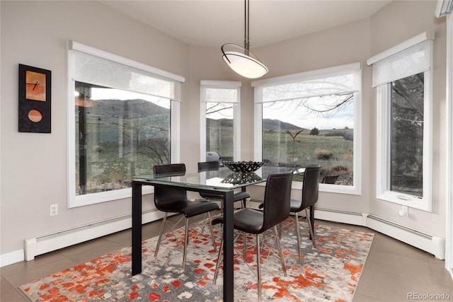 dining area featuring a baseboard radiator, baseboards, and tile patterned flooring