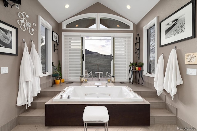 bathroom with recessed lighting, a bath, and lofted ceiling