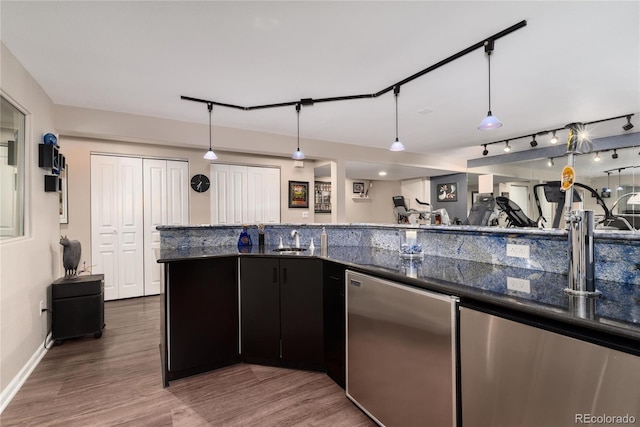 kitchen with a sink, wood finished floors, refrigerator, and dark countertops