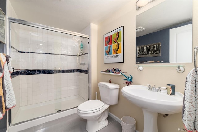 bathroom with baseboards, a stall shower, tile patterned flooring, toilet, and a sink