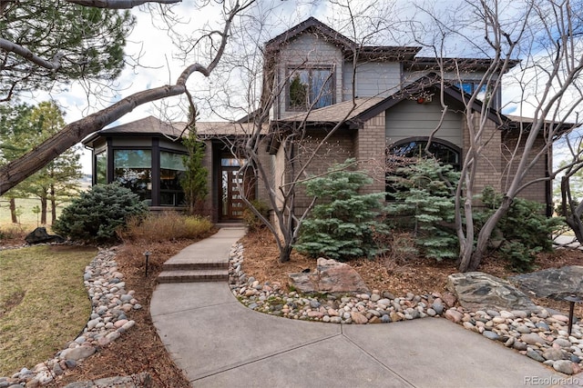 view of front of home featuring brick siding and roof with shingles