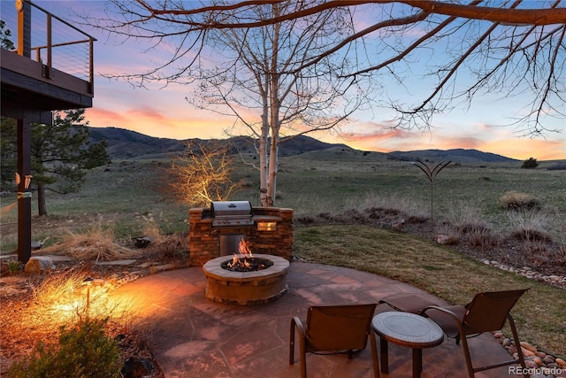 view of patio / terrace with an outdoor fire pit, a mountain view, and a grill