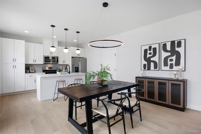 dining area with light wood-type flooring and recessed lighting