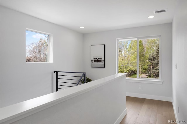 hall with an upstairs landing, hardwood / wood-style floors, visible vents, baseboards, and recessed lighting