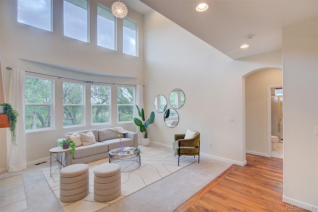 1839 Caleta Trl, Longmont, CO 80504 - living area with arched walkways, a high ceiling, recessed lighting, and light wood-type flooring