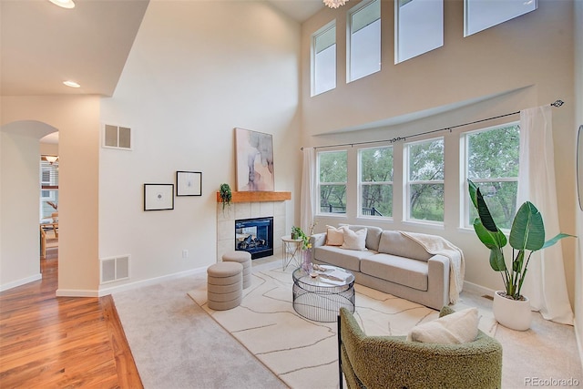 1839 Caleta Trl, Longmont, CO 80504 - living room with arched walkways, a high ceiling, light wood finished floors, a tiled fireplace, and recessed lighting