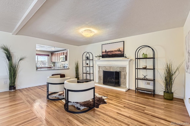 living room featuring a premium fireplace, a textured ceiling, and light hardwood / wood-style flooring