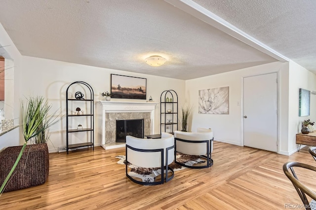 living room featuring light hardwood / wood-style flooring, a fireplace, and a textured ceiling