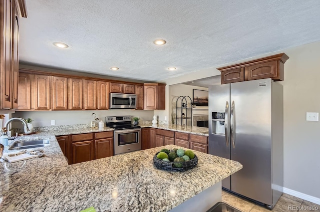 kitchen with sink, light stone countertops, kitchen peninsula, and appliances with stainless steel finishes