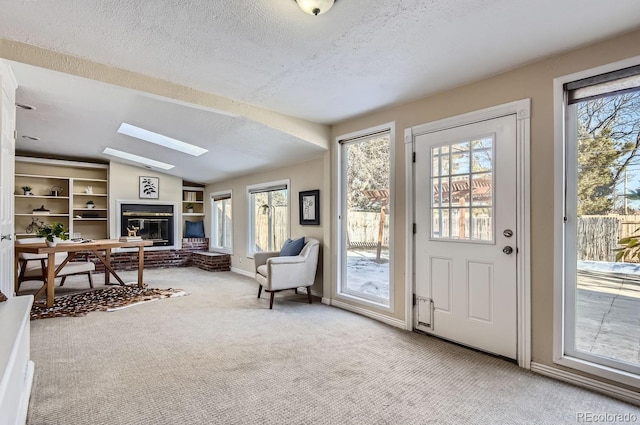 carpeted foyer entrance featuring lofted ceiling with skylight and a textured ceiling