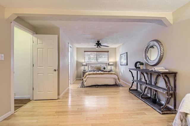 bedroom with ceiling fan, light hardwood / wood-style floors, and a textured ceiling