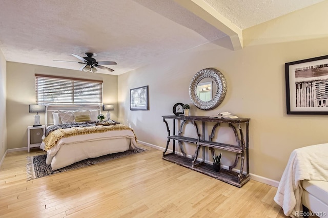 bedroom with ceiling fan, a textured ceiling, and light wood-type flooring