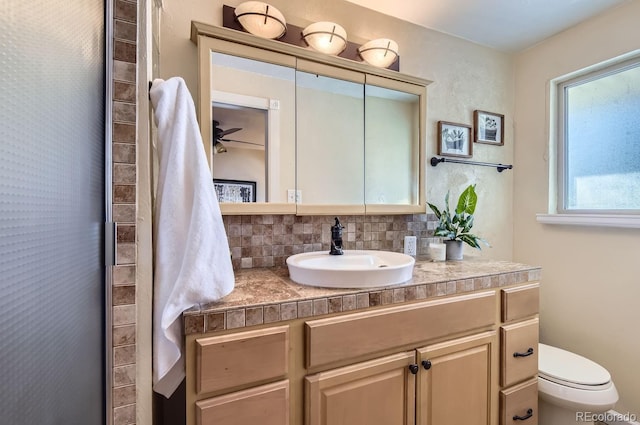 bathroom with tasteful backsplash, vanity, a shower with shower door, and toilet