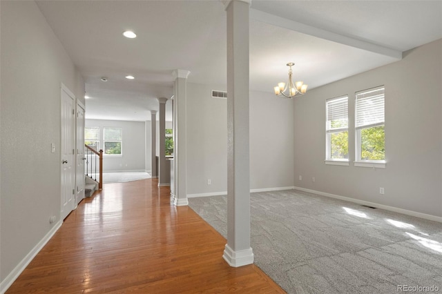 interior space featuring ornate columns, wood-type flooring, a chandelier, and plenty of natural light