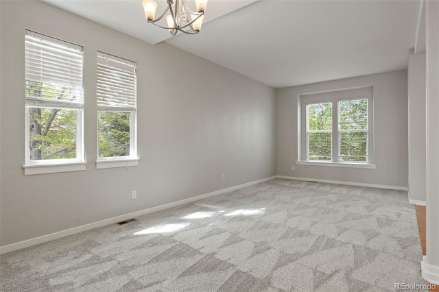 unfurnished room with an inviting chandelier and light colored carpet