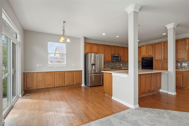 kitchen featuring decorative light fixtures, stainless steel appliances, light wood-type flooring, and a healthy amount of sunlight