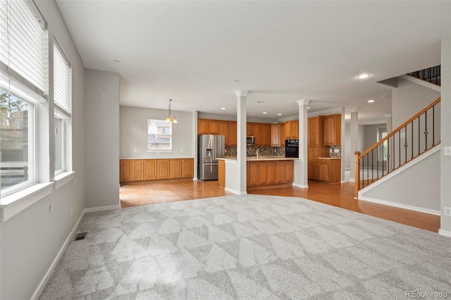 unfurnished living room with light wood-type flooring, decorative columns, and sink