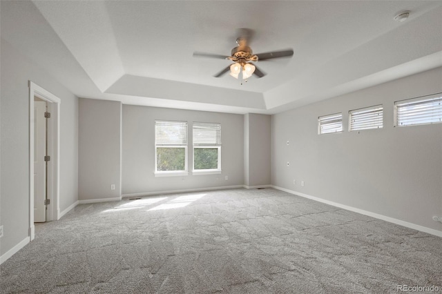 carpeted spare room featuring a tray ceiling and ceiling fan