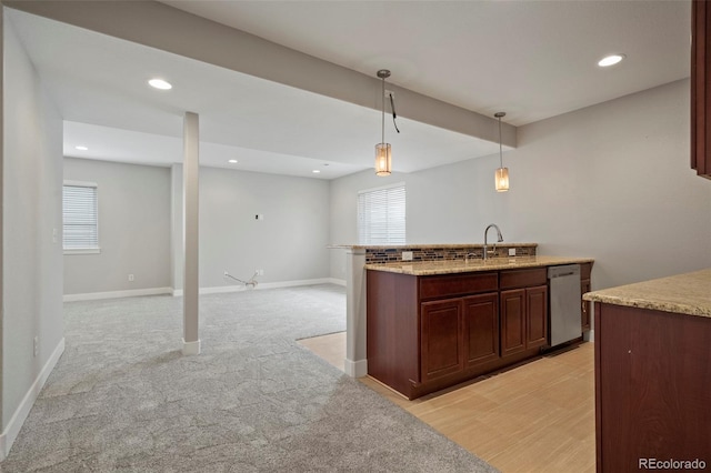 kitchen with sink, hanging light fixtures, light carpet, light stone countertops, and stainless steel dishwasher