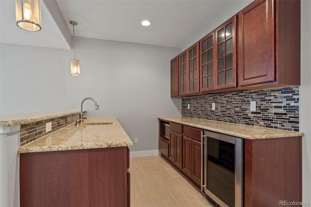 kitchen with decorative backsplash, wine cooler, light stone countertops, pendant lighting, and sink