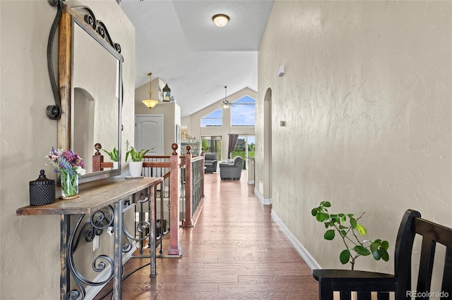 8101 Wynstone Dr, Windsor, CO 80550 - hallway featuring lofted ceiling, wood finished floors, arched walkways, baseboards, and a textured wall
