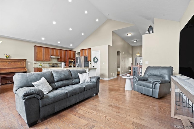 8101 Wynstone Dr, Windsor, CO 80550 - living room with high vaulted ceiling, arched walkways, light wood-style flooring, recessed lighting, and baseboards