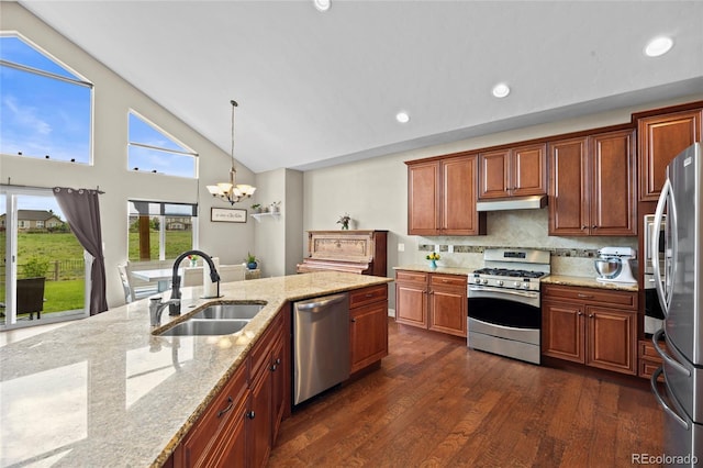 8101 Wynstone Dr, Windsor, CO 80550 - kitchen with stainless steel appliances, a sink, under cabinet range hood, dark wood finished floors, and a chandelier