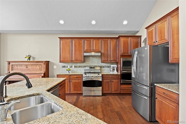 8101 Wynstone Dr, Windsor, CO 80550 - kitchen featuring stainless steel appliances, a sink, under cabinet range hood, dark wood-style flooring, and brown cabinets