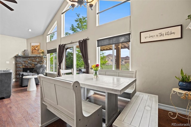 8101 Wynstone Dr, Windsor, CO 80550 - dining room with high vaulted ceiling, wood finished floors, a stone fireplace, a ceiling fan, and baseboards