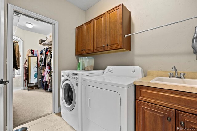 8101 Wynstone Dr, Windsor, CO 80550 - laundry area featuring washing machine and dryer, cabinet space, light carpet, and light tile patterned floors