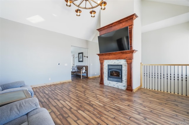 living room featuring hardwood / wood-style flooring, a fireplace, high vaulted ceiling, and a notable chandelier