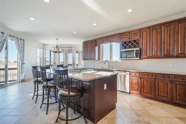 kitchen with stainless steel appliances, sink, decorative light fixtures, an inviting chandelier, and a kitchen island