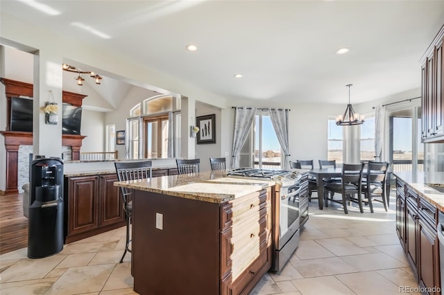 kitchen with a kitchen breakfast bar, high end stainless steel range oven, decorative light fixtures, a notable chandelier, and a center island