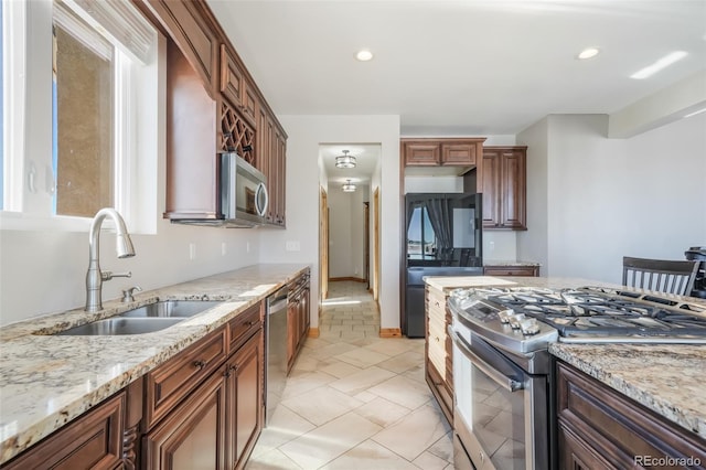 kitchen featuring light stone countertops, appliances with stainless steel finishes, and sink