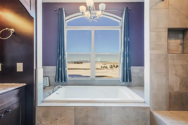 bathroom with tiled bath, vanity, and an inviting chandelier