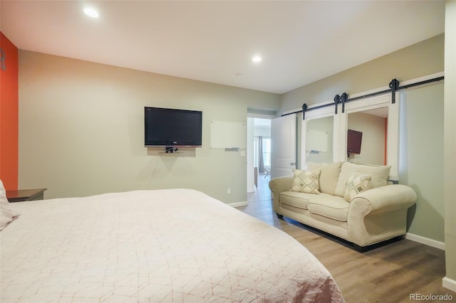 bedroom featuring wood-type flooring and a barn door