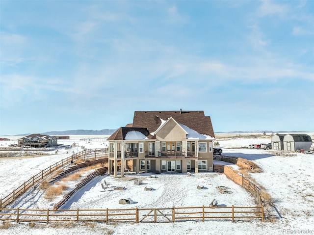 snow covered back of property featuring a balcony and a storage unit