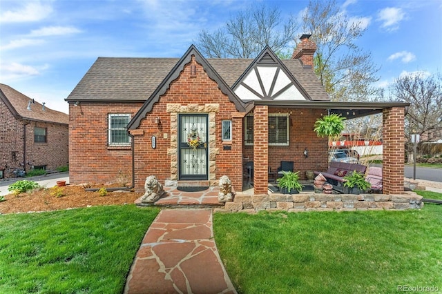 2995 Albion St, Denver, CO 80207 - tudor home with roof with shingles, a front lawn, a chimney, and brick siding