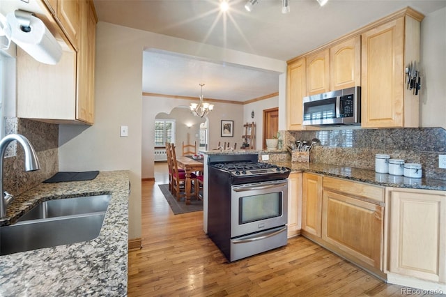 2995 Albion St, Denver, CO 80207 - kitchen featuring light wood-type flooring, light brown cabinets, appliances with stainless steel finishes, and a sink